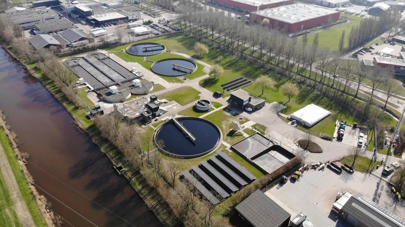 Rioolwaterzuivering met zonnepanelen langs het water, gezien vanuit de lucht