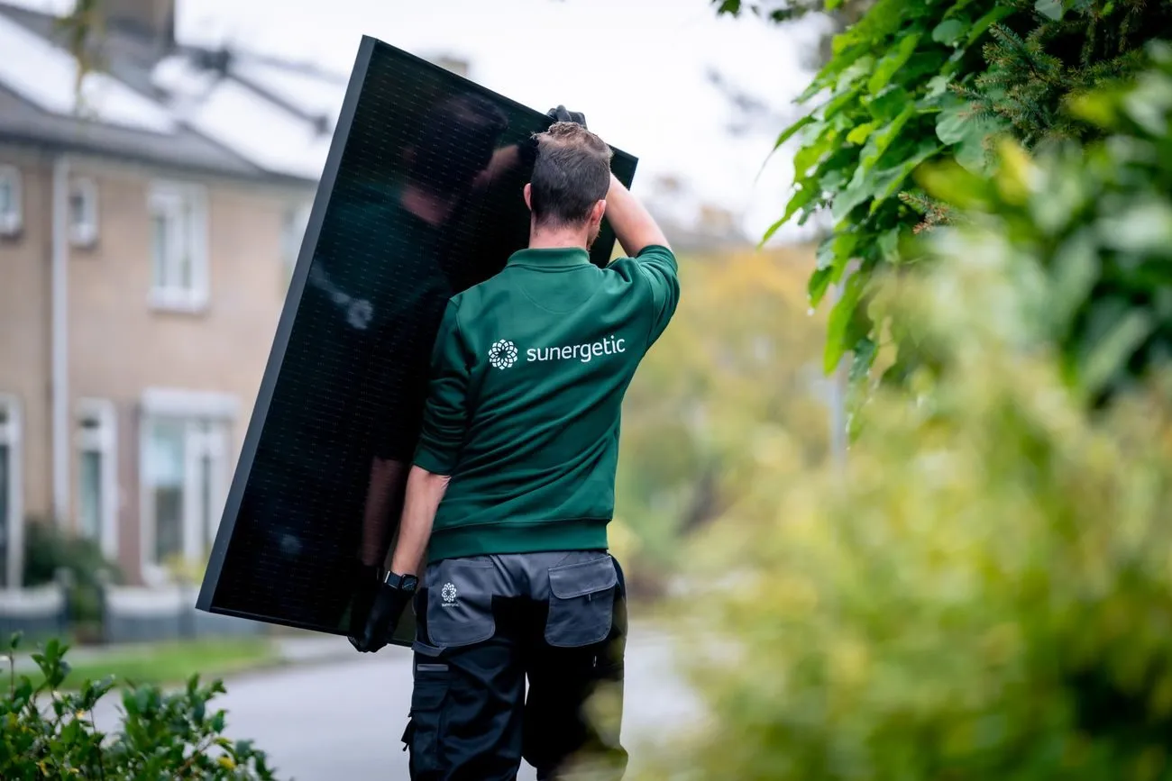Monteur van Sunergetic draagt een zonnepaneel naar de installatie